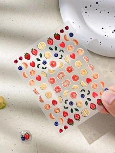 Detail of 3D embossed fruit nail stickers featuring strawberries and orange slices
