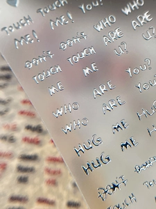 Macro detail of 3D silver embossed nail stickers with metallic text and heart motifs