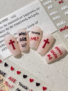 Detailed view of matte pink coffin press-on nails with Gothic lettering and red crosses