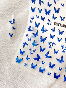 Detail of blue butterfly nail stickers with rhinestones on white fabric texture
