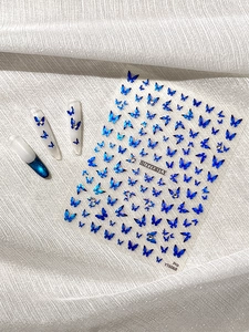 Detailed view of blue gradient butterfly nail stickers on display tips with silk background