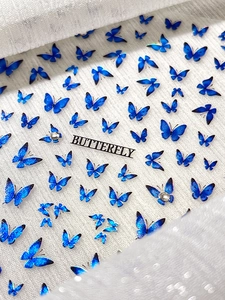 Macro detail of blue glitter butterfly nail art decals with rhinestones on lace background