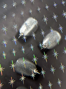 Macro shot of silver star-accented nail art charms with glittery frosted finish