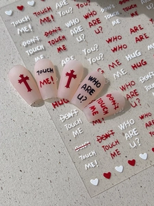 Detail of gothic style nail stickers with black English phrases and red cross designs