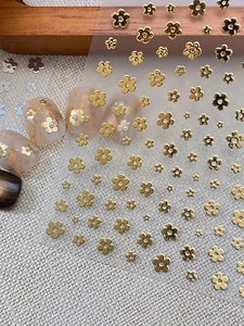 Detailed view of golden flower nail stickers with varied sizes on marble manicured nails