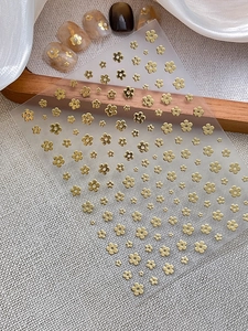 Detailed view of gold 3D flower nail stickers with metallic relief and pearl accents