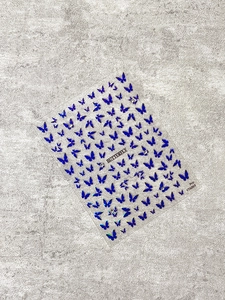 Macro detail of laser holographic blue butterfly nail art stickers on stone texture