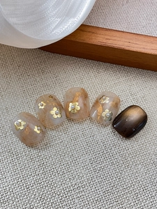 Detail of marble texture nails with gold foil, metallic flowers and pearl embellishments