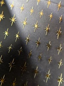 Macro shot of minimalist gold star nail art stickers with a sparkling metallic finish