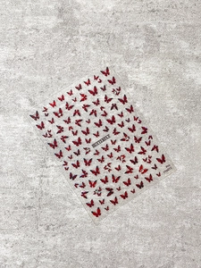Detail of red butterfly nail art stickers with crystal rhinestones on marble background