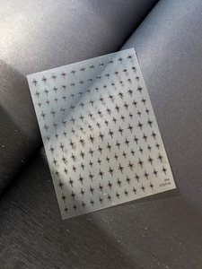 Macro shot of minimalist black starburst nail art stickers on a matte finish sheet