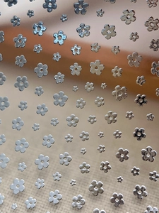 Macro detail of silver floral nail art stickers in various sizes with metallic finish
