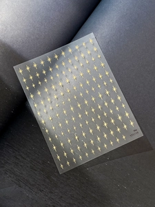 Detail showing golden star nail stickers with metallic starburst patterns on a dark surface