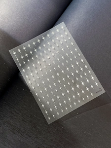 Macro view of transparent nail stickers featuring white starburst and sparkle patterns