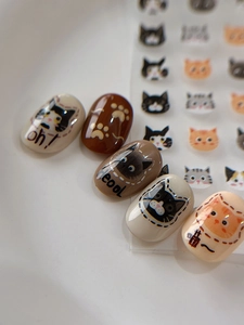 Close-up of cute cartoon cat nail art stickers featuring paw prints and kitten patterns