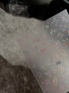 Macro shot of holographic laser butterfly and fireworks patterns on luxury nail art stickers