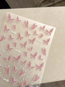 Macro shot of 3D embossed pink butterfly nail stickers with delicate white outline
