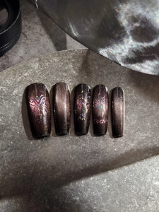 Detail of dark brown cat-eye press-on nails with laser butterfly and stars patterns