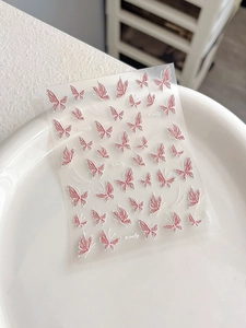 Macro detail of embossed pink butterfly nail art stickers with delicate 3D relief texture