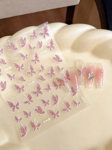 Detail of pink butterfly nail stickers with pearls on a textured cream tray