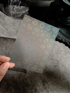 Detailed macro of holographic laser firework nail stickers showing colorful glitter effects