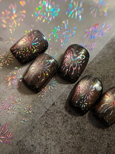 Detailed view of holographic fireworks nail stickers on dark cat-eye manicure effect
