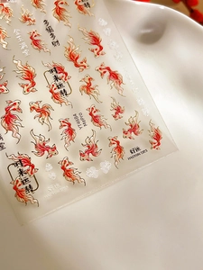 Macro detail of red and gold koi fish nail art stickers with lucky Chinese characters