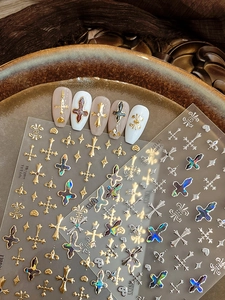 Detailed view of gold and silver cross nail art stickers on a vintage metal tray