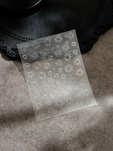 Detail shot of laser silver firework and floral nail art stickers on a gray texture
