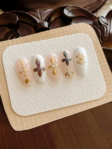Detail of pink and white press-on nails with golden gothic crosses and iris relief