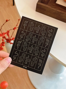 Detail of YT 75 nail stickers featuring twenty golden snake patterns on black background