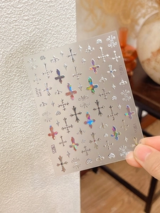 Close-up of chrome silver gothic cross nail stickers with 3D metallic texture design