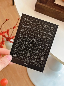 Macro detail of Chinese auspicious cloud nail art stickers in gold on black background