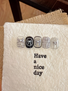 Macro view of French style nail art stickers with embossed pearls and bowknot details