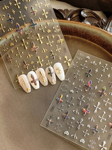Detailed macro view of 3D metallic cross and heart nail art stickers with relief effect