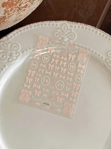 Close-up of 3D embossed nail art stickers with elegant pink bows and pearl patterns