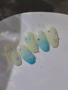 Macro detail of ice blue gradient press-on nails with 3D snowflakes and rhinestones