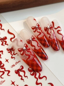 Close-up of balletcore red bow nail stickers with white pearls and plaid patterns