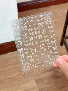 Detail view of embossed bow and pearl nail art stickers with tweed and floral patterns