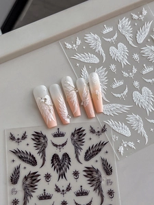 Detail of wing and crown nail art decals applied over a soft pink gradient base