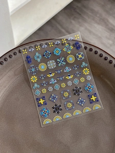 Detail of embossed bohemian nail art stickers with vintage blue and yellow mandala patterns