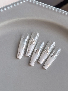 Detail of gradient coffin nails with silver stars and rhinestones on a ceramic tray