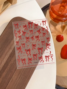 Detail of red bow nail stickers with ribbons and stars on a transparent backing sheet