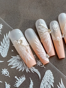 Macro view of coffin nails with matte gradient, 3D angel wings, and pearl accents