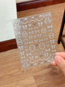 Detail view of 5D embossed bow and plaid nail art stickers with black and white patterns