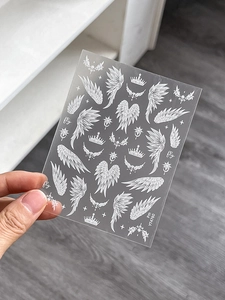 Detailed sheet of white wing and crown nail stickers for DIY manicure decoration