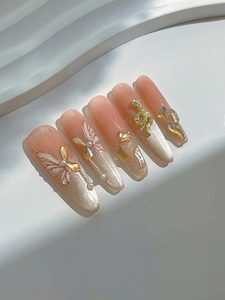 Detailed view of nude pink gradient press-on nails with 3D metal butterfly and rhinestones