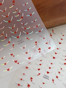 Macro view of holographic silver lines and red heart nail art stickers with adhesive back
