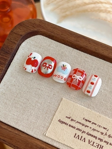 Macro detail of short round handmade press-on nails with red apple and 3D bow art