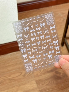 3D embossed nail art stickers with white bow patterns and pearl chain details
